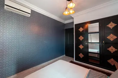 a bedroom with a blue wall with a window at La maison du soleil in Oulad Akkou
