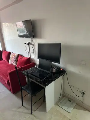 a room with a desk with a computer and a red couch at Bright & comfortable apartment in Marrakech