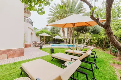 a patio with chairs and an umbrella and a pool at Dar Saada Private Villa in Marrakech