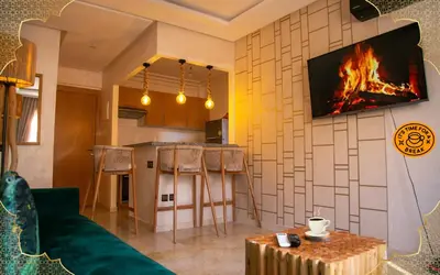 a living room with a fireplace and a tv on a wall at Cozy, Nice appartement,swimming pool,Wifi in Marrakech