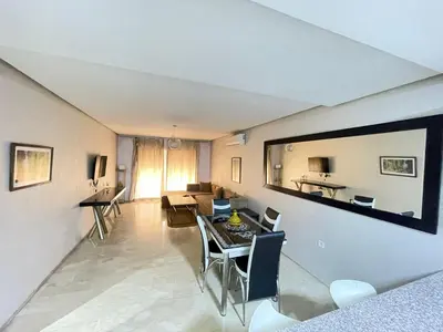 a living room with a table and a dining room at Appartement élégant, Escapade parfaite à Marrakech in Marrakech