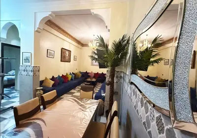 a living room with a blue couch and a palm tree at Appart Nour in Marrakech