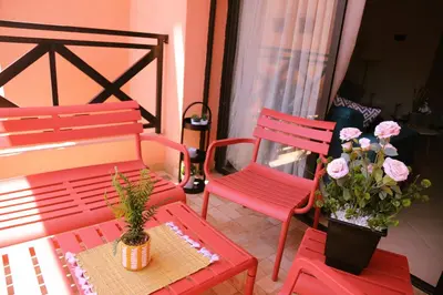 two red chairs and a table and flowers on a balcony at Charming apartment in a tourist village Premium village in Marrakech