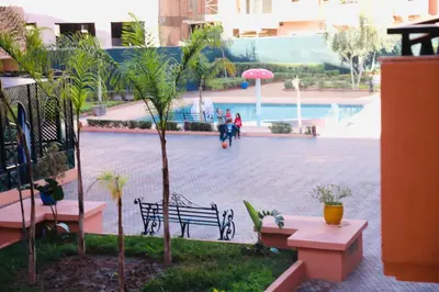 a park with a bench and palm trees and a fountain at Charming apartment in a tourist village Premium village in Marrakech
