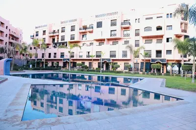 a swimming pool in front of a large building at Charming apartment in a tourist village Premium village in Marrakech