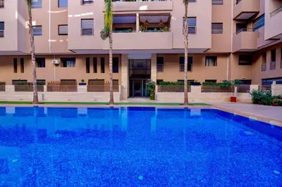 a swimming pool in front of a building with palm trees at 5 Star City Oasis Modern and Cozy in Marrakech