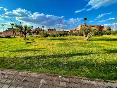 a field of grass with trees and buildings in the background at 5 Star City Oasis Modern and Cozy in Marrakech