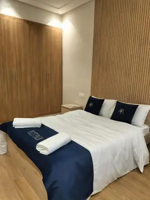 a bedroom with a large bed with blue and white sheets at Villa Moderne 5 chambres vue sur Atlas in Marrakech