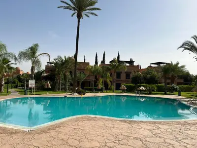 a large swimming pool with a palm tree in the background at A Cosy Maison avec un accès direct à la piscine in Marrakech