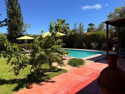 a swimming pool in a yard with an umbrella at DAR ENNAGA - Havre de paix, avec piscine chauffée , à 10 minutes de Marrakech in Marrakech