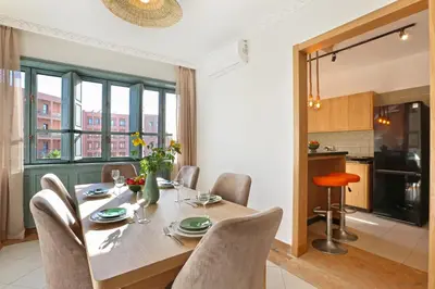 a dining room with a table and chairs and a kitchen at Spacious 3Br Apartment-Pool&AC- Heart of Marrakech- Hivernage in Marrakech