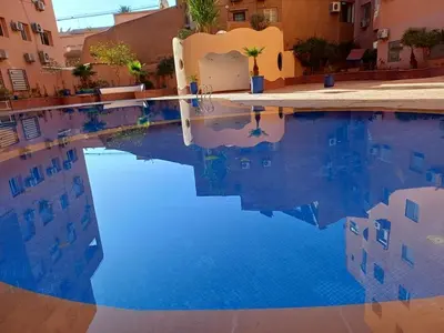 a swimming pool with blue water in front of a building at Gueliz Appartement in Marrakech