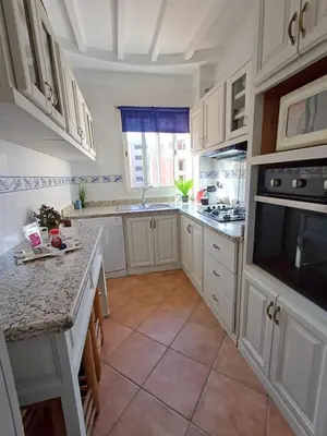 a kitchen with white cabinets and a large window at Gueliz Appartement in Marrakech