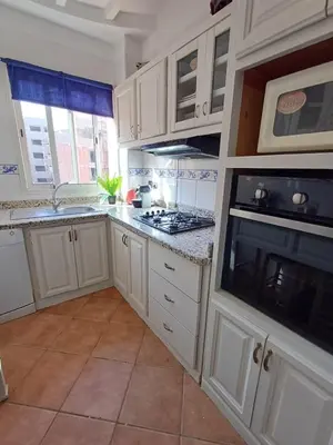 a kitchen with white cabinets and a stove top oven at Gueliz Appartement in Marrakech