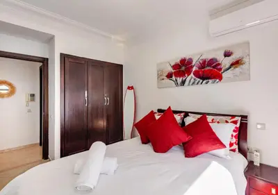 a bedroom with a large white bed with red pillows at Appartement Moderne & Spacieux au Cœur de Guéliz et Proche Majorelle in Marrakech