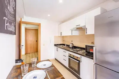 a kitchen with white cabinets and a stainless steel refrigerator at Joli cocon à Marrakech Balcon privé et confort in Marrakech