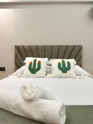 a bed with two white pillows with cactus pillows at Menara Prestige Duplex 4BR with Pool Access in Marrakech