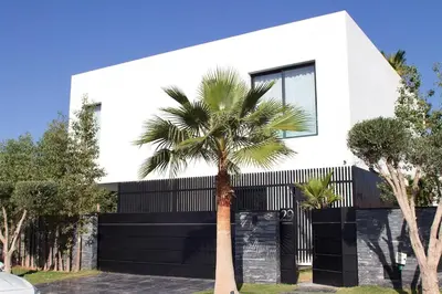 a palm tree in front of a white house at Villa PALM GOLF AMELKIS in Marrakech