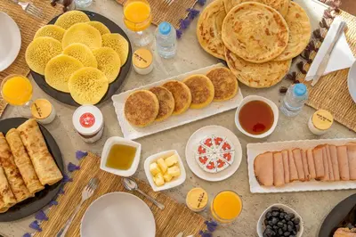 a table topped with plates of food and pancakes at Villa Nabil by TheCasaEdition Cinema, Heated pool & Jaccuzi in Marrakech