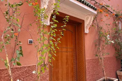 a wooden door on a pink building with flowers at Riad Amanar in Marrakech