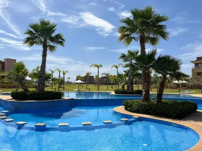 a swimming pool with palm trees in a resort at Luxury Appartement Golf and Pool in Marrakech
