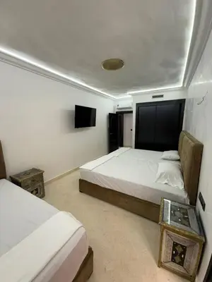 a bedroom with two beds and a flat screen tv at BIG comfort with pool North Gueliz RIAD Ambiance in Marrakech