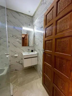 a bathroom with a wooden door and a sink at Appartement Centre Ville Gueliz Parking Inclus in Marrakech