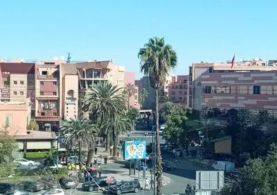 a city with palm trees and a street with cars at Escapade citadine avec balcon et confort total in Marrakech