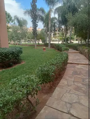 a walkway through a park with trees and grass at Appartement cosy moderne luxe in Marrakech