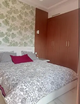 a bedroom with a large bed and wooden cabinets at Appartement cosy moderne luxe in Marrakech