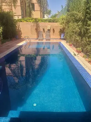 a swimming pool with blue water in front of a building at Villa Marrakech haut standing avec piscine et architecture arabesque in Marrakech