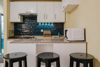 a kitchen with two black stools and a microwave at Appartement Relax & Confort au Cœur de Marrakech in Marrakech