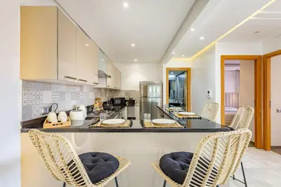 a kitchen with a counter with chairs in it at Sakina Appartement Luxe Gueliz in Marrakech