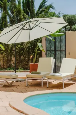 two chairs and an umbrella next to a pool at Very comfortable villa in the heart of Marrakech in Marrakech