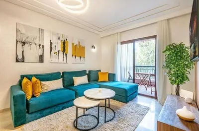 a living room with a blue couch and a table at Charme Central Appart Gueliz en Face La gare in Marrakech