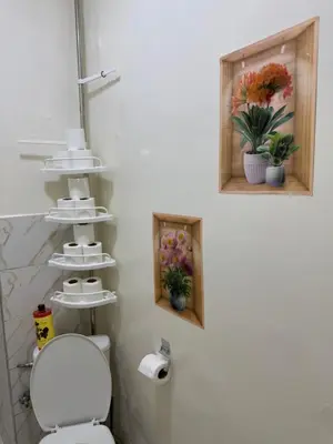 a bathroom with a toilet and two pictures on the wall at Only 5-minutes walk to airport, your perfect choice for an early or late flight in Oulad Akkou