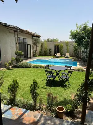 a yard with a table and chairs next to a pool at Villa familiale, piscine privée sans vis-à-vis in Marrakech