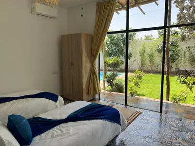 two beds in a room with a large window at Villa familiale, piscine privée sans vis-à-vis in Marrakech
