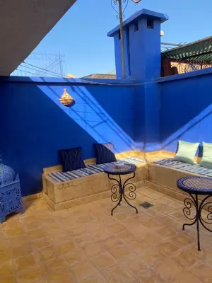 a blue wall with two benches and tables on a patio at Le Riad l'étoile beldi in Marrakech