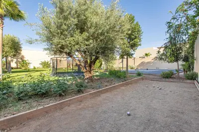 a tree in the middle of a park with a building at Villa Safiya, Piscine Chauffée & jeux in Marrakech
