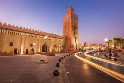 a building with a clock tower in the middle of a street at light stay in Marrakech