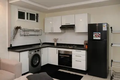 a kitchen with white cabinets and a black refrigerator at Apartment for rent ,Duplex in Marrakech