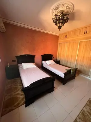 a bedroom with two beds and a chandelier at Marrakech gulize in Marrakech