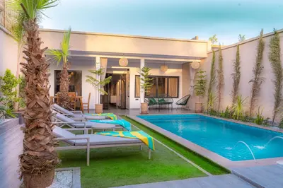 a swimming pool with lounge chairs next to a house at Villa loujain in Marrakech