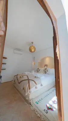 a bedroom with a large bed with a wooden frame at Riad 2 Ksour Marrakesh in Marrakech