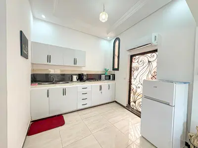 a kitchen with white cabinets and a refrigerator at Évasion Douce avec jardin, terrasse et piscine privée in El Aggada