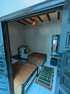 a room with two beds and a door at Riad du village in Marrakech