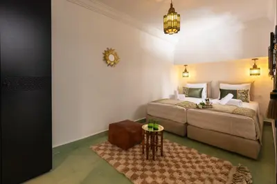 a bedroom with two beds and a table at Riad Zehra in Marrakech