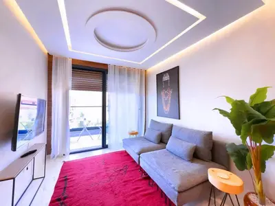 a living room with a couch and a tv at Appt de Luxe avec Terrasse,PiscinePartagée & wifi in Marrakech