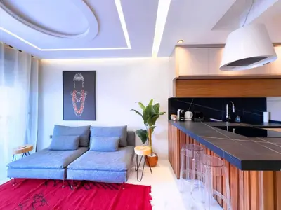 a living room with a blue couch and a kitchen at Appt de Luxe avec Terrasse,PiscinePartagée & wifi in Marrakech